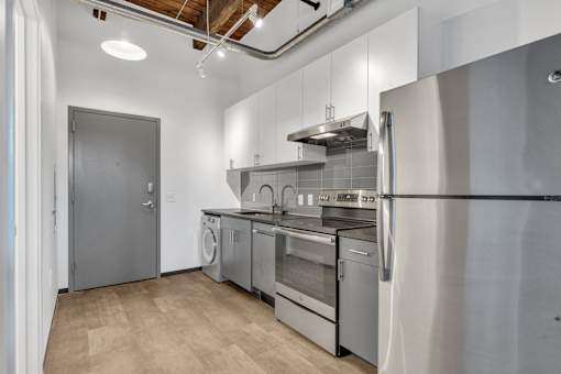 A modern kitchen with stainless steel appliances and wooden flooring.