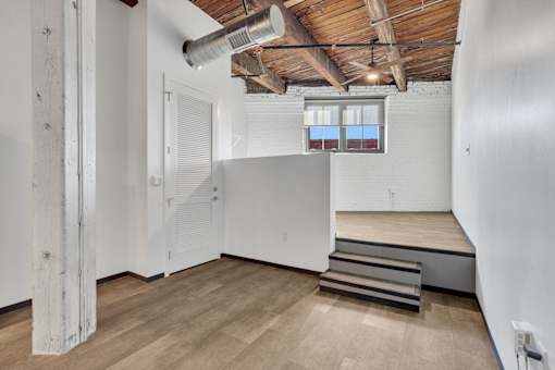 A room with wooden floors and a window with a red curtain.