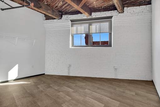 A room with a white brick wall and wooden flooring.