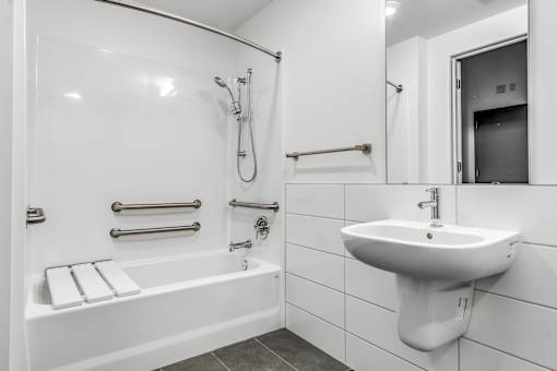 A white bathroom with a sink, bathtub, and mirror.