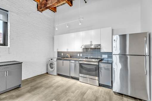 A modern kitchen with stainless steel appliances and wooden flooring.
