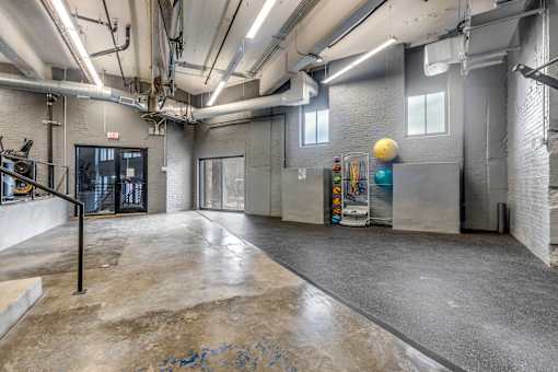 A spacious room with concrete floors and exposed pipes on the ceiling.