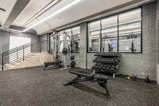 A gym with a bench, weights, and a mirror.