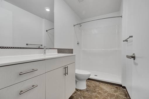 A white bathroom with a toilet, sink, and shower.