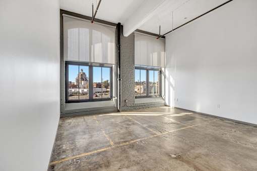 A large empty room with a view of the city through the windows.