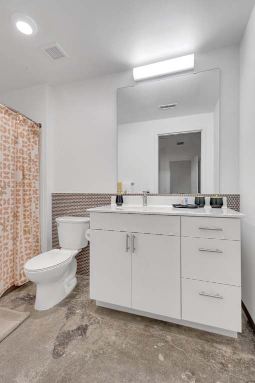 A white bathroom with a toilet, sink, and mirror.