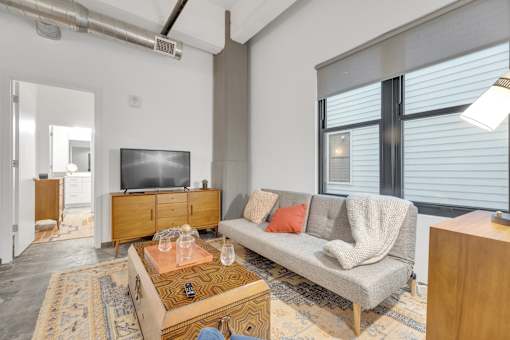 A living room with a grey couch, a wooden coffee table, and a television.