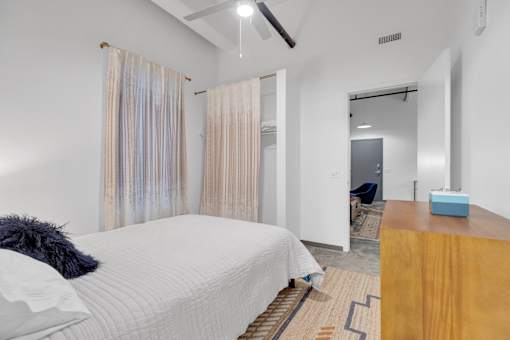A bedroom with a bed, a wooden desk, and a mirror.