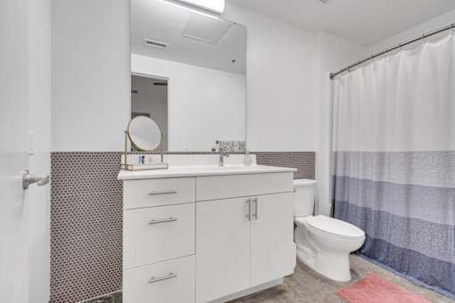 A white bathroom with a toilet, sink, and shower curtain.