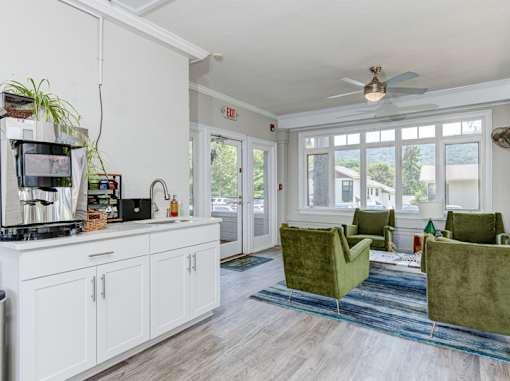 A kitchen with white cabinets and a green chair.