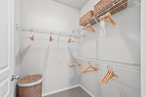 A white closet with clothes hanging on hangers.