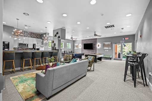 A living room with a grey couch and a kitchen area in the background.