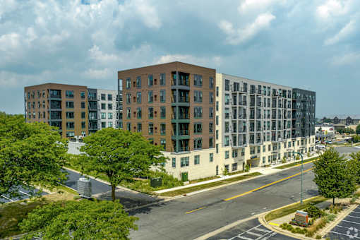 A large apartment complex with multiple buildings and a parking lot in front.