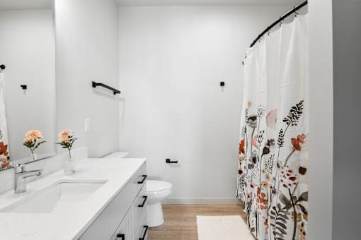 A white bathroom with a floral shower curtain.
