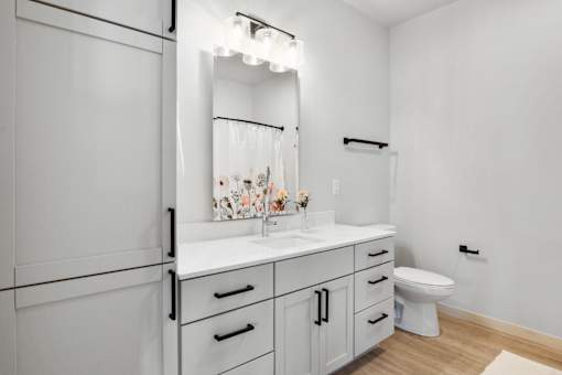 A white bathroom with a toilet, sink, and mirror.