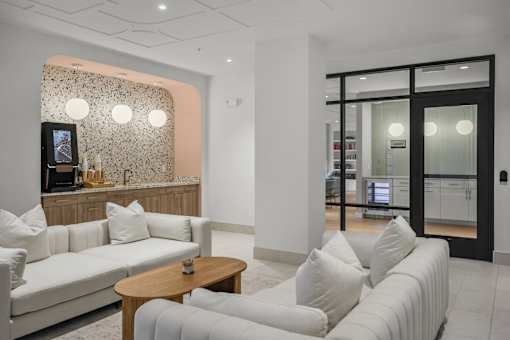 A white couch with a wooden table in front of a wall with a patterned wallpaper.
