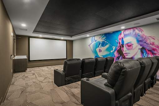 A movie theater with black chairs and a large screen.