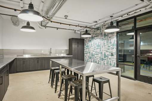 A kitchen with a table and stools in the foreground and a glass wall in the background.