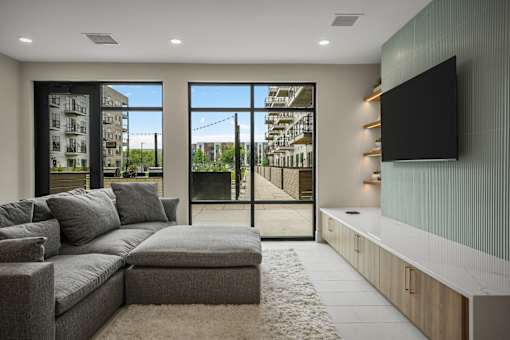 A modern living room with a grey sofa and a flat screen TV mounted on the wall.