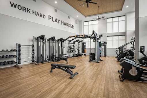 A gym with a variety of equipment and a ceiling fan.