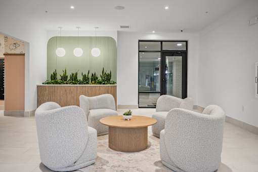 A modern waiting room with grey chairs and a wooden table.