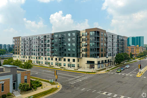 A large apartment building is situated on a street corner with a traffic light and a crosswalk.