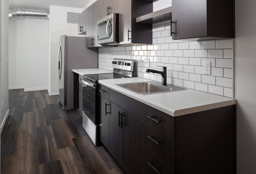 A kitchen with black cabinets and a white counter top at The Landing at 1001 NP, Fargo, ND 58102