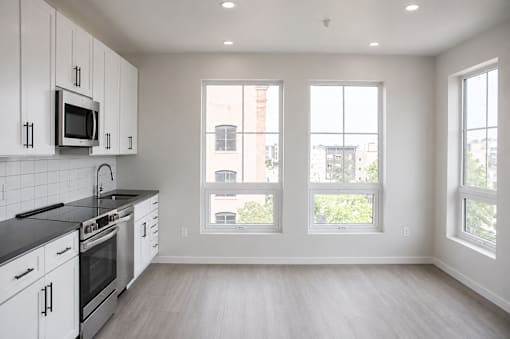Modern kitchen with large windows and light flooring at The Avery - Residential Apartments, Fargo