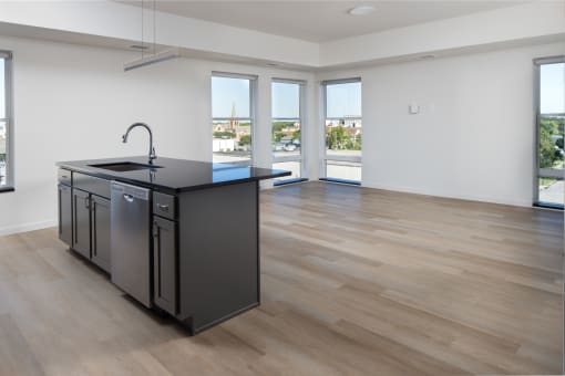 an open kitchen and living room with a large window and a black counter top at Riverhouse Apartments, Fargo, North Dakota