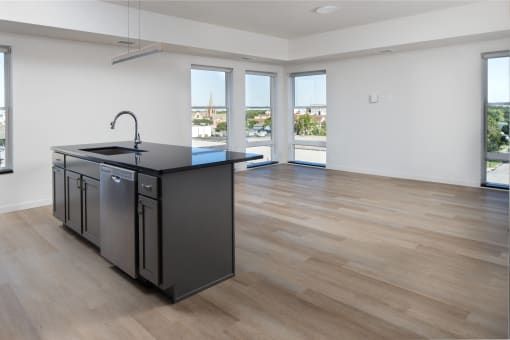 an open kitchen and living room with a large window and a black counter top at Riverhouse Apartments, Fargo, ND 58102