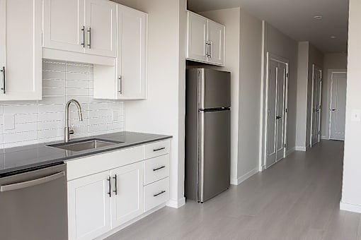 Contemporary kitchen with gray countertops and white backsplash at The Avery - Residential Apartments, Fargo