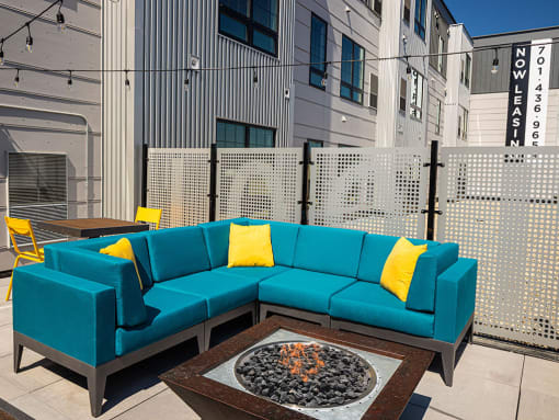 a patio with a blue couch and yellow pillows at The Landing at 1001 NP, Fargo, ND 58102