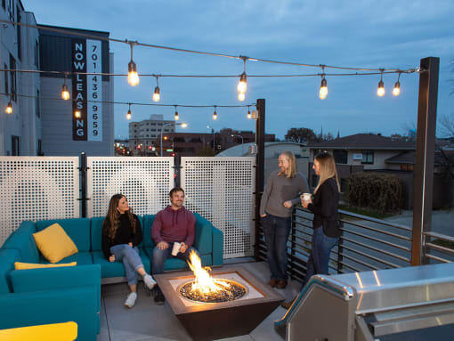 a group of people sitting around a fire pit on a rooftop patio at The Landing at 1001 NP, Fargo, ND 58102