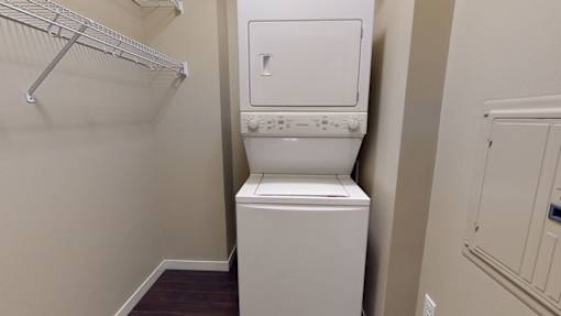 A white dryer is in a small laundry room.