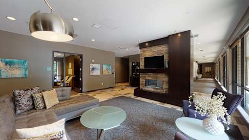 A modern living room with a grey sofa and a glass coffee table.