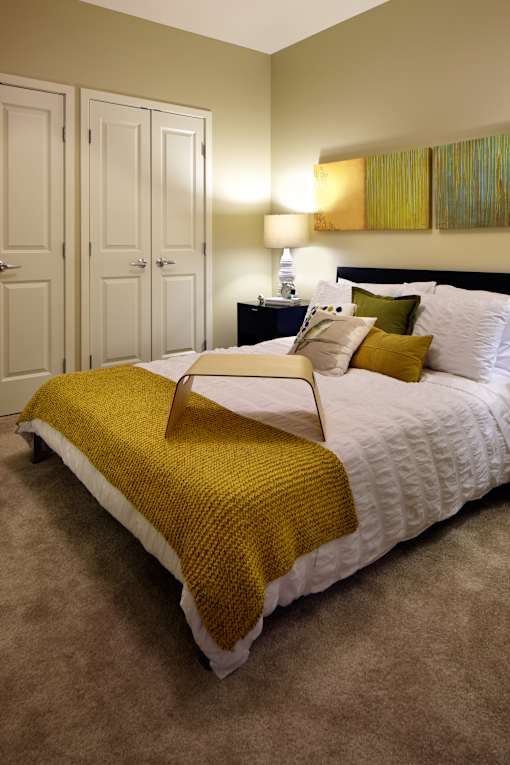 A bed with a yellow blanket and white pillows.