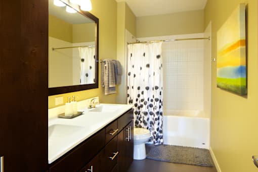 A bathroom with a sink, mirror, and shower.