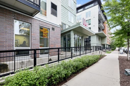 a sidewalk in front of a building with a black fence