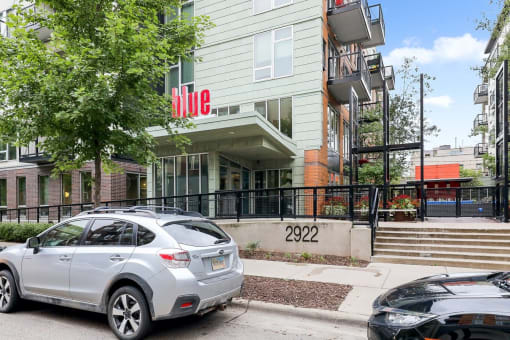 an apartment building with a silver car parked in front of it