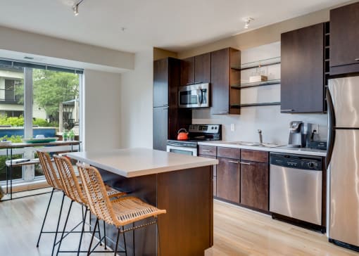 a kitchen with wooden cabinets and stainless steel appliances and a counter with two chairs