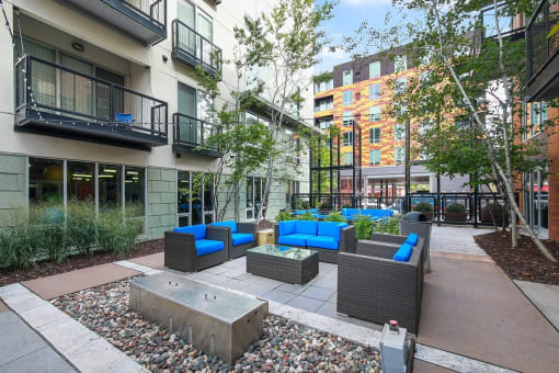 a courtyard with couches and a fire pit in front of a building