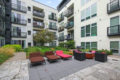 an outdoor area with lounge chairs in front of an apartment building