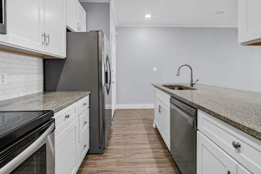 A kitchen with white cabinets and a granite countertop.