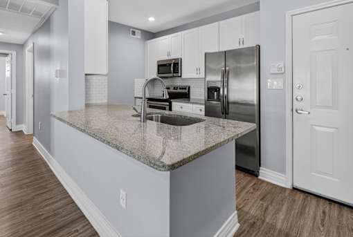 A kitchen with a granite countertop and stainless steel appliances.