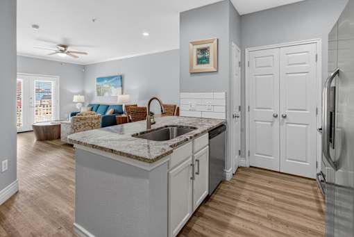 A kitchen with a marble countertop and wooden floors.