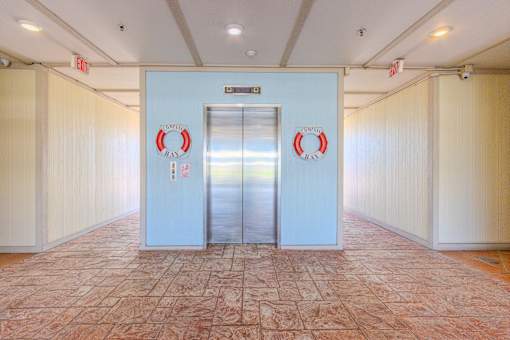 A hallway with a blue door and red lifebuoys on it.