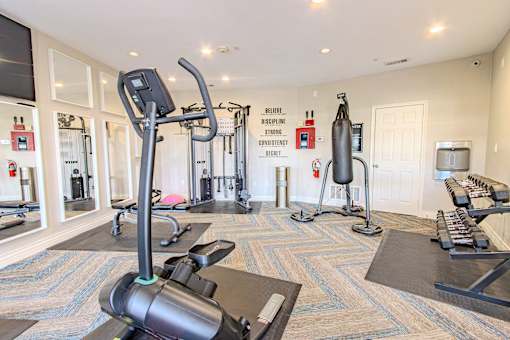 A gym with a variety of equipment including treadmills, weights, and exercise machines.
