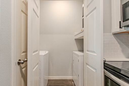 A white kitchen with a door open.