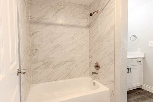A white bathroom with a marble tile wall.