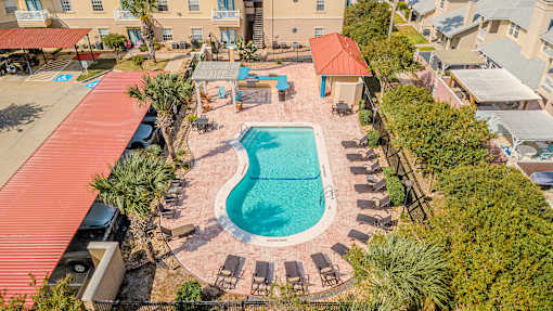 An aerial view of a pool surrounded by a red roof and palm trees.